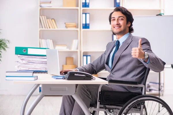 Young handsome employee in wheelchair at the office