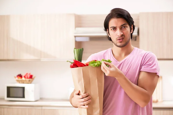 Joven hombre guapo con verduras en la cocina — Foto de Stock