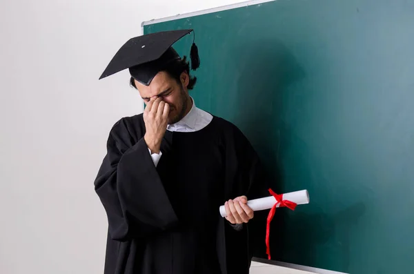 Estudante graduado na frente do quadro verde — Fotografia de Stock