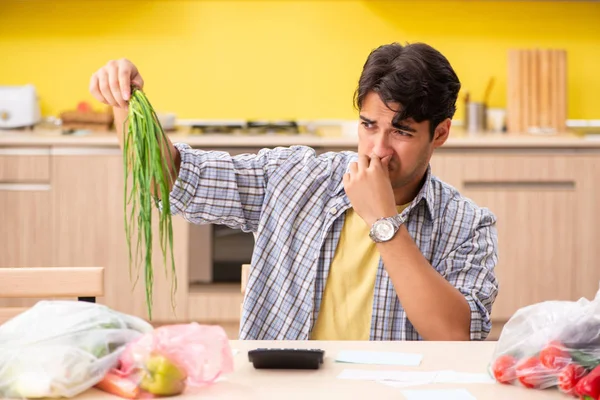 Young man calculating expences for vegetables in kitchen — Stock Photo, Image