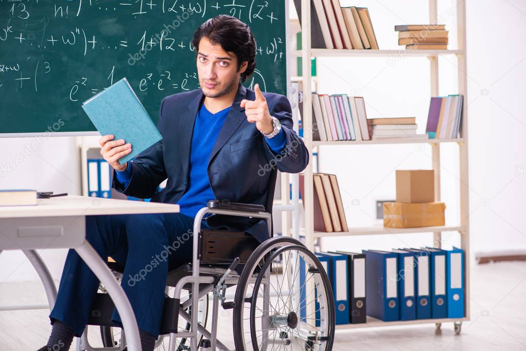 Young handsome man in wheelchair in front of chalkboard 