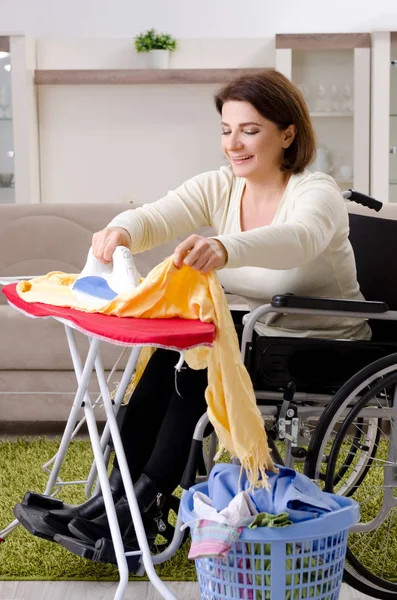 Femme en fauteuil roulant repassage à la maison — Photo