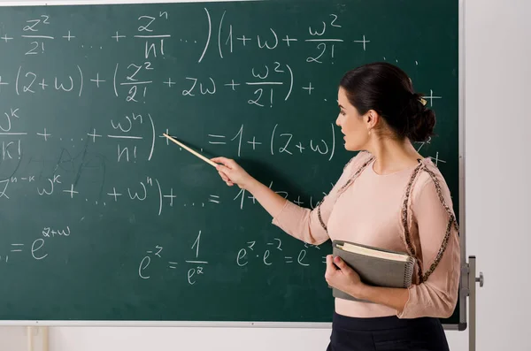 Female teacher standing in front of chalkboard — Stock Photo, Image