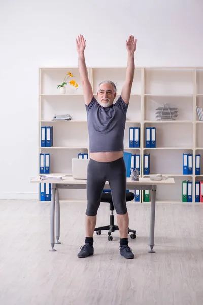 Witte baard oude man werknemer doen oefeningen in het kantoor — Stockfoto