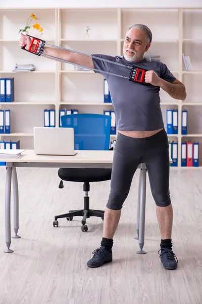 Vit skäggig gammal man anställd gör övningar på kontoret — Stockfoto