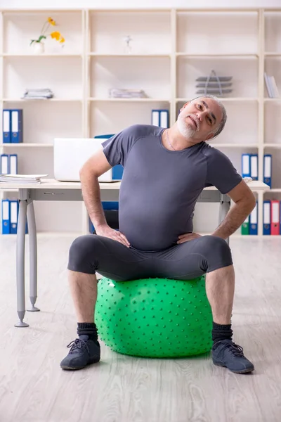 Mitarbeiter mit weißem Bart macht Übungen im Büro — Stockfoto