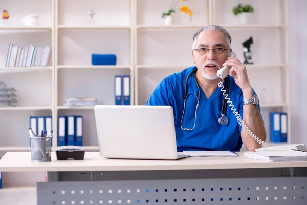 Dokter tua berjanggut putih bekerja di klinik — Stok Foto