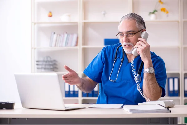 Beyaz sakallı yaşlı doktor klinikte çalışan — Stok fotoğraf