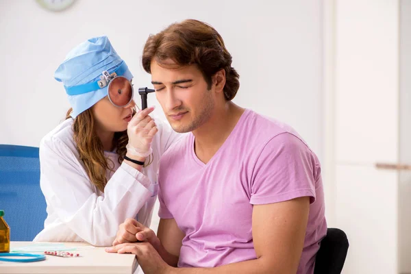 Joven hombre guapo visitando joven médico otorrinolaringólogo —  Fotos de Stock