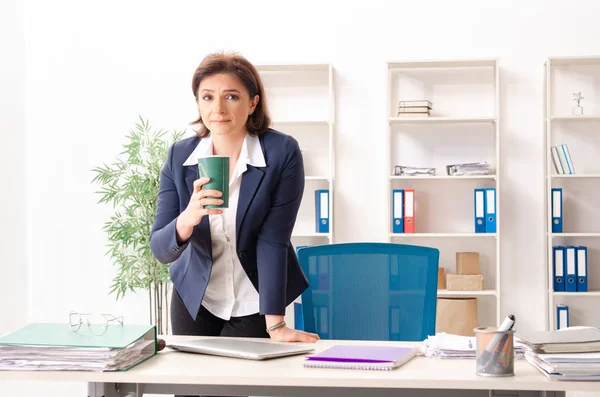 Middelbare leeftijd vrouwelijke werknemer zitten op kantoor — Stockfoto