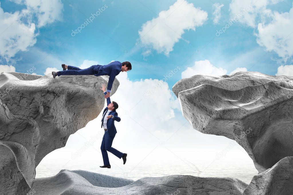 Businessman offering helping hand to falling colleague