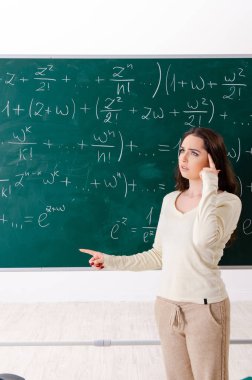 Karatahtanın önünde genç bayan matematik öğretmeni.  