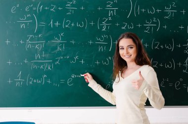 Karatahtanın önünde genç bayan matematik öğretmeni.  