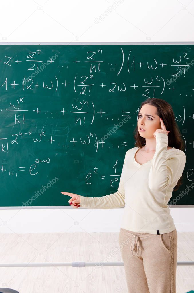 Young female math teacher in front of chalkboard  