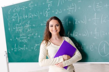 Karatahtanın önünde genç bayan matematik öğretmeni.  