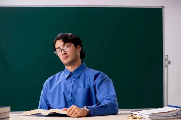 Jeune professeur masculin devant un tableau noir — Photo