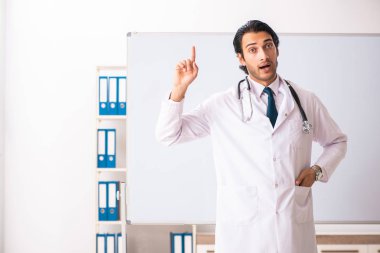 Genç doktor beyaz tahtanın önünde. 