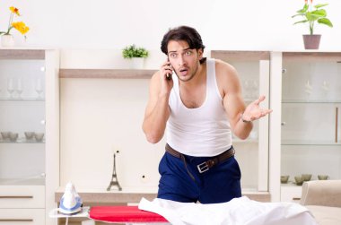 Genç adam yatak odasında ütü yapıyor.