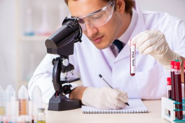 Genç yakışıklı laboratuvar asistanı hastanede kan örnekleri test ediyor. 