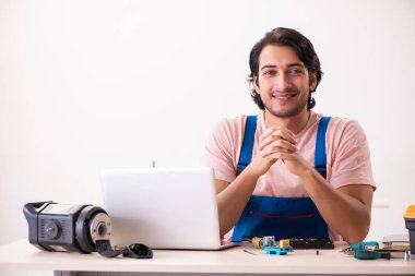 Genç bir erkek müteahhit bilgisayar tamir ediyor.  