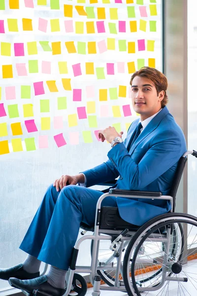 Молодой красивый мужчина в инвалидной коляске со многими противоречивыми приоритетами — стоковое фото