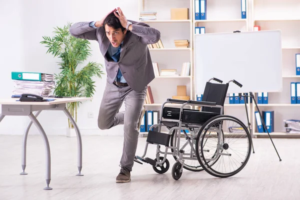 Young handsome employee in wheelchair at the office