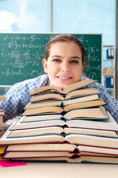 Vrouwelijke student met vele boeken die zitten in de klas — Stockfoto