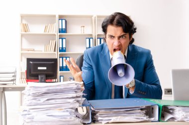 Genç ve yakışıklı çalışan ofiste oturuyor. 