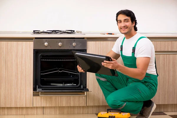 Joven contratista reparación de horno en la cocina —  Fotos de Stock