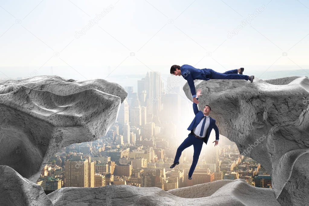 Businessman offering helping hand to falling colleague