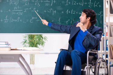 Yakışıklı delikanlı kara tahta önünde tekerlekli sandalyede 