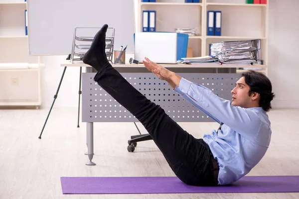Giovane bel dipendente maschio che fa esercizi in ufficio — Foto Stock