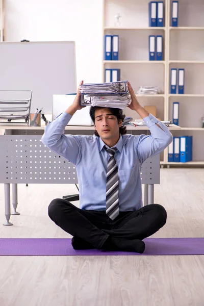 Young handsome male employee doing exercises in the office — Stock Photo, Image