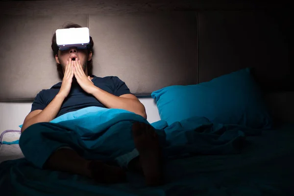 Jovem jogando jogos de computador à noite na cama — Fotografia de Stock