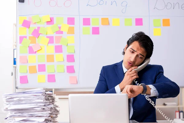 Jovem e bonito funcionário na frente do quadro branco com lista de tarefas — Fotografia de Stock