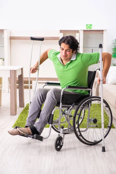 Jovem homem bonito em cadeira de rodas em casa — Fotografia de Stock