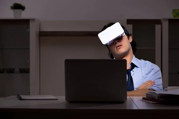 Empleado joven con gafas virtuales por la noche en la oficina — Foto de Stock