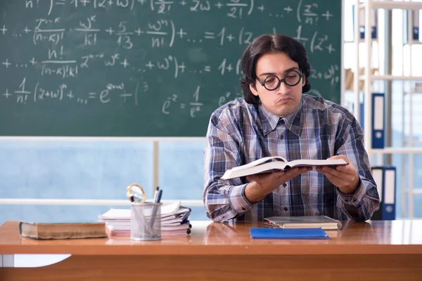 Joven profesor de matemáticas divertido delante de pizarra —  Fotos de Stock