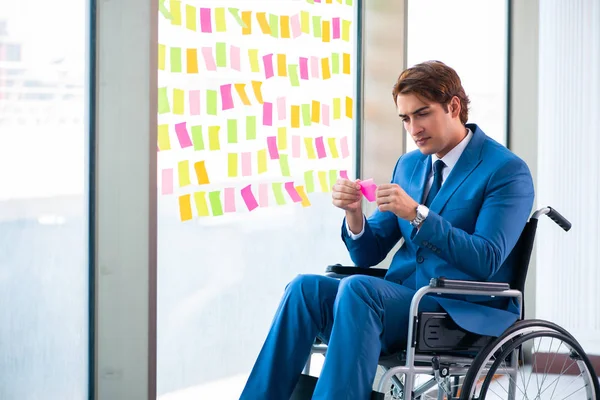 Birçok çelişkili önceliği olan tekerlekli sandalyedeki genç yakışıklı adam.