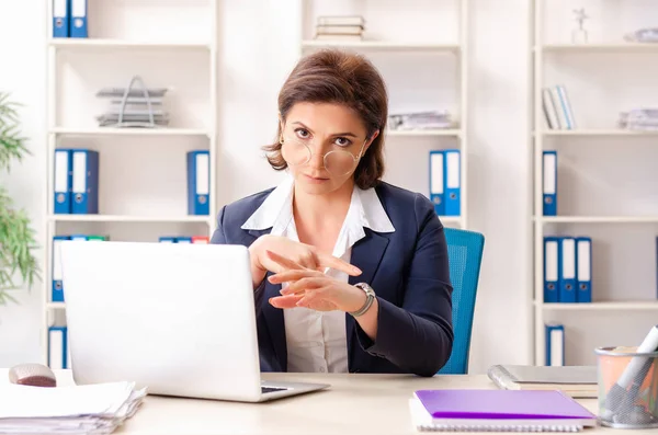 Middle-aged female employee sitting at the office