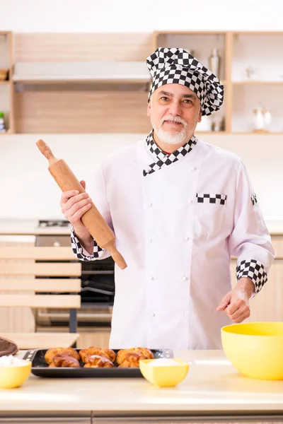 Old male baker working in the kitchen