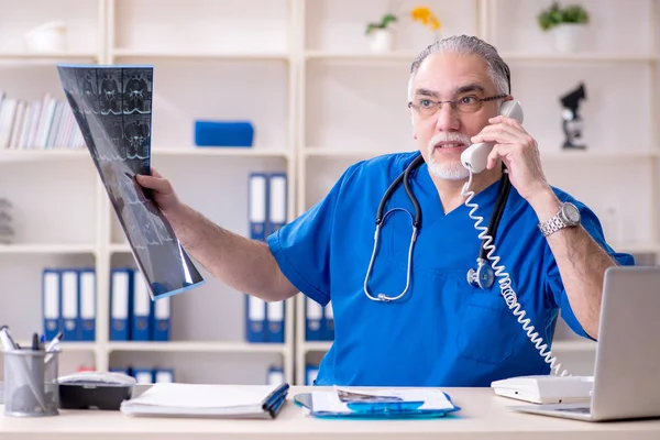 Bílá vousatý starý lékař radiolog pracující v klinice — Stock fotografie