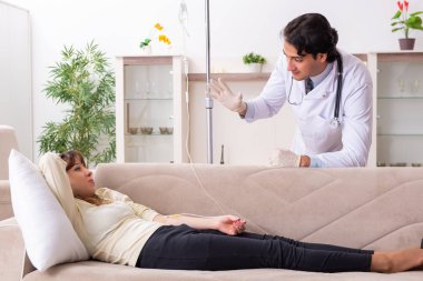 Genç, yakışıklı doktor, kadın hastayı evinde ziyaret ediyor. 