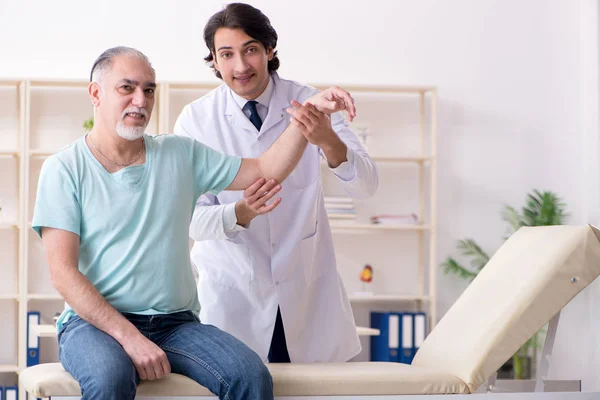 Viejo visitando joven doctor masculino — Foto de Stock