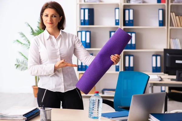 Middle-aged female employee doing exercises in the office