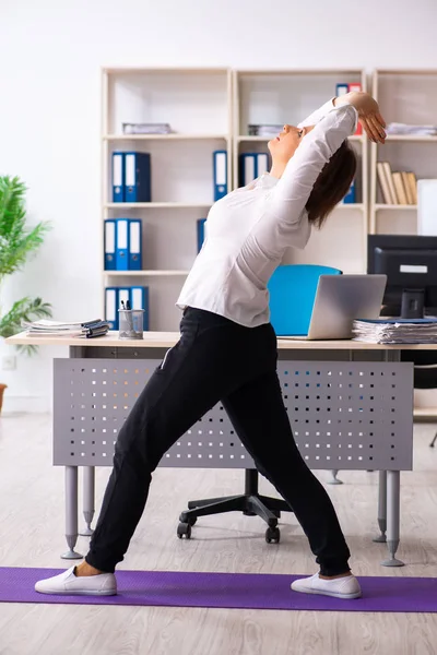 Empleada de mediana edad haciendo ejercicios en la oficina —  Fotos de Stock