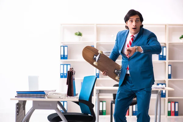 Jovem empresário bonito com longboard no escritório — Fotografia de Stock