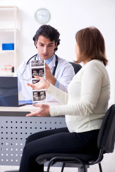 Vieille femme enceinte visitant jeune médecin masculin — Photo