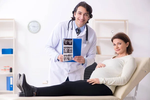 Velha mulher grávida visitando jovem médico masculino — Fotografia de Stock