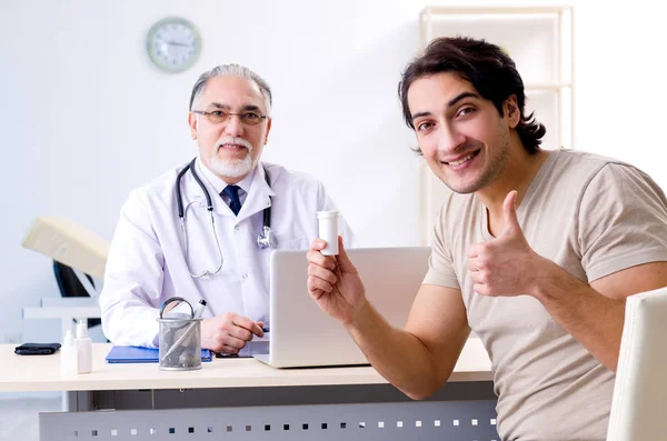 Jovem visitando velho médico masculino — Fotografia de Stock